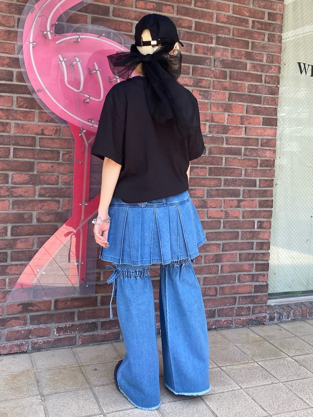 ブルー系のスカート、ブラック系のTシャツ/カットソー、ブラック系のキャップを着用したレディースの春コーディネートの5枚目の写真