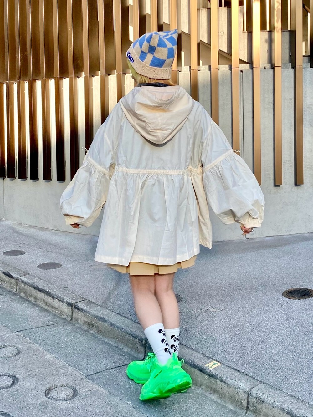 ベージュ系のナイロンジャケット、ブラック系のポロシャツ、ベージュ系のスカートを着用したレディースの春コーディネートの4枚目の写真