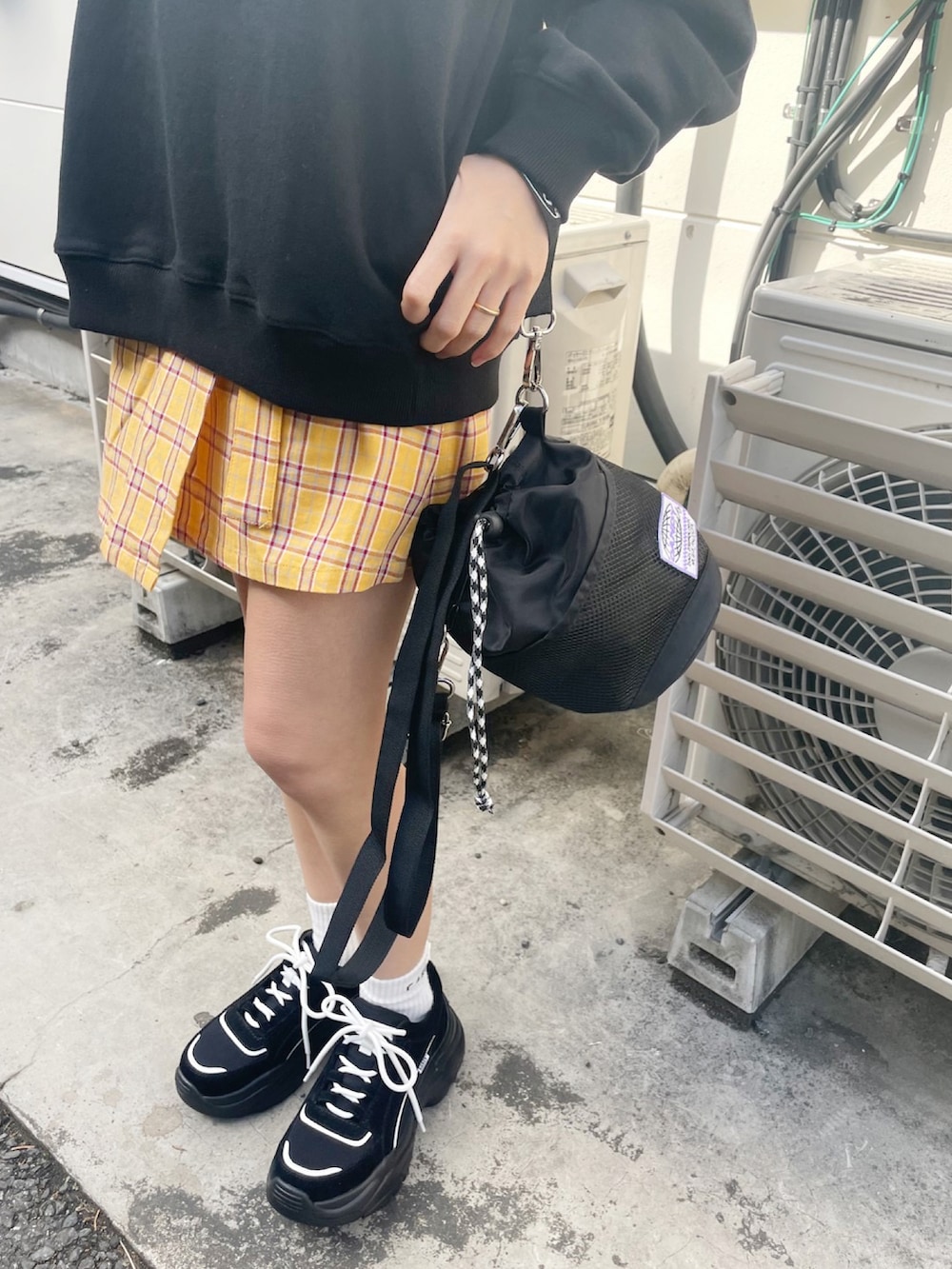 ブラック系のパーカー、イエロー系のスカート、ブラック系のショルダーバッグを着用したレディースの冬コーディネートの3枚目の写真