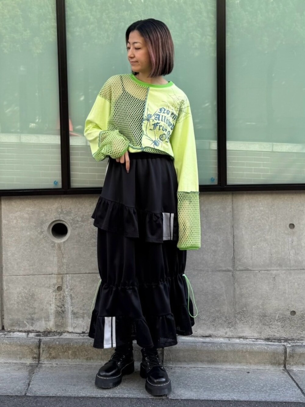 グリーン系のTシャツ/カットソー、ブラック系のスカートを着用したレディースの春コーディネートの2枚目の写真