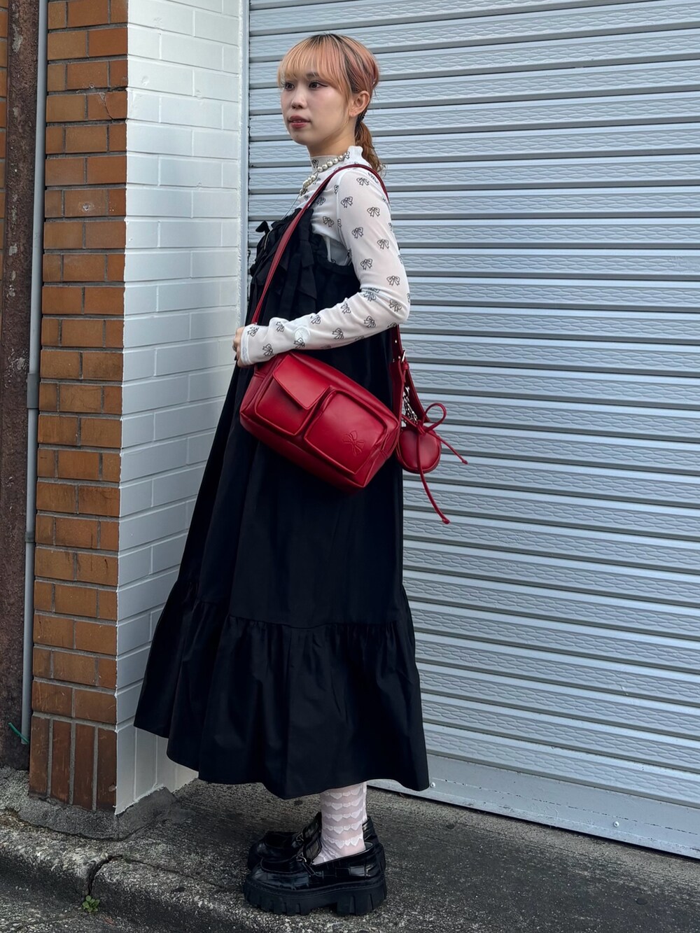 ブラック系のワンピース、ホワイト系のその他トップス、レッド系のショルダーバッグを着用したレディースの春コーディネートの3枚目の写真