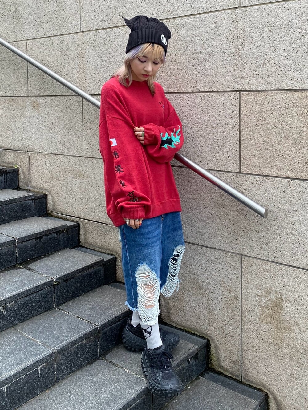 ブルー系のデニムパンツ、レッド系のニット/セーター、ブラック系のニットキャップ/ビーニーを着用したレディースの秋コーディネートの3枚目の写真