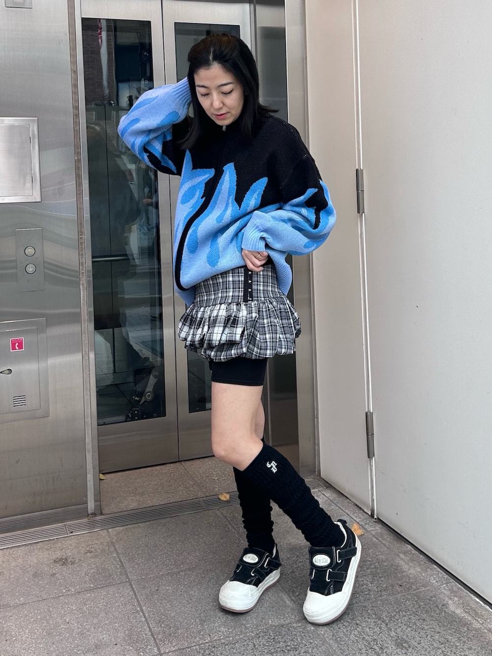 グレー系のスカート、ブラック系のニット/セーター、ブラック系のソックス/靴下を着用したレディースの秋コーディネートの4枚目の写真