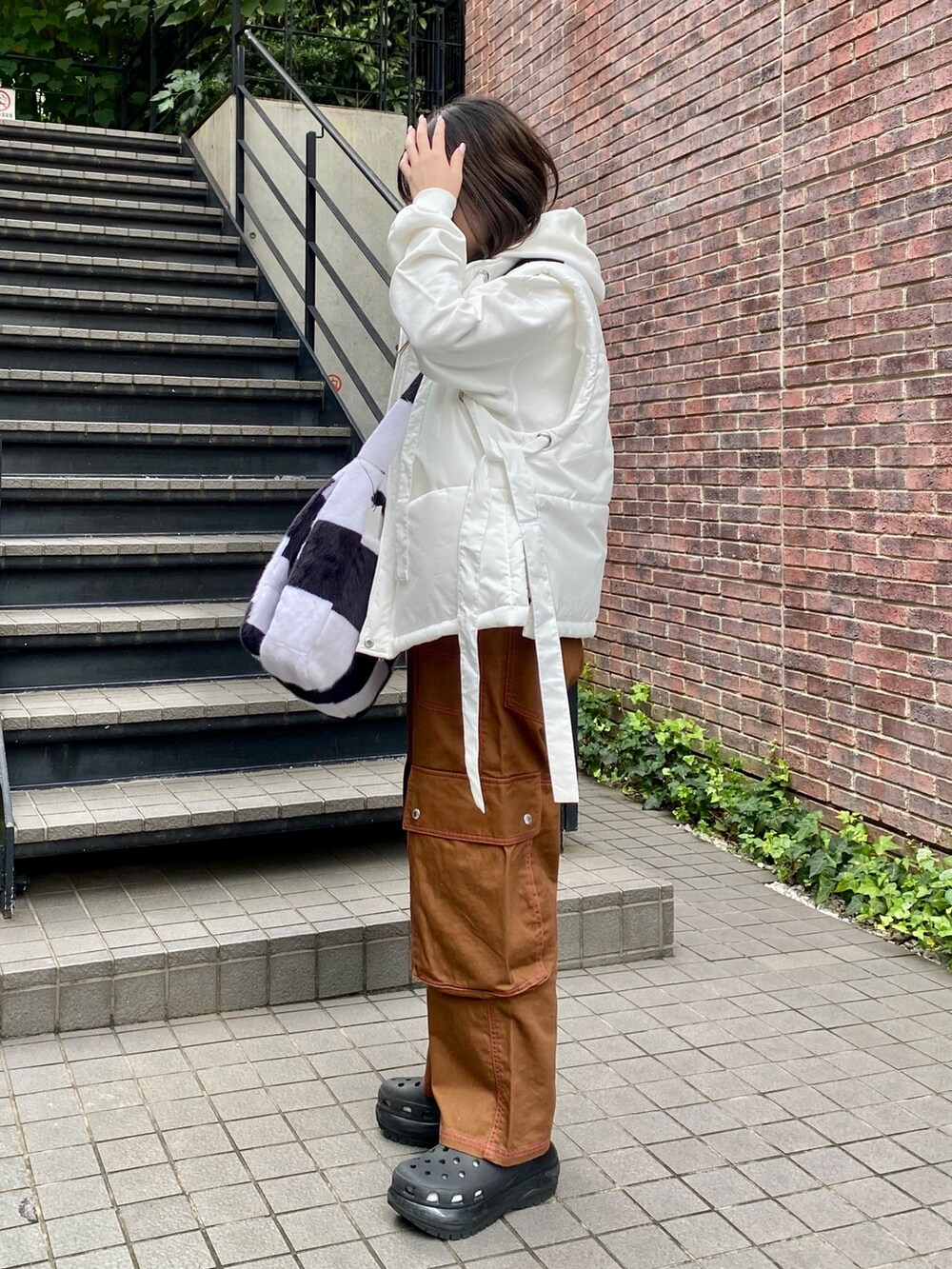 ホワイト系のショルダーバッグ、ブラウン系のカーゴパンツ、ホワイト系のパーカーを着用したレディースの秋コーディネートの3枚目の写真