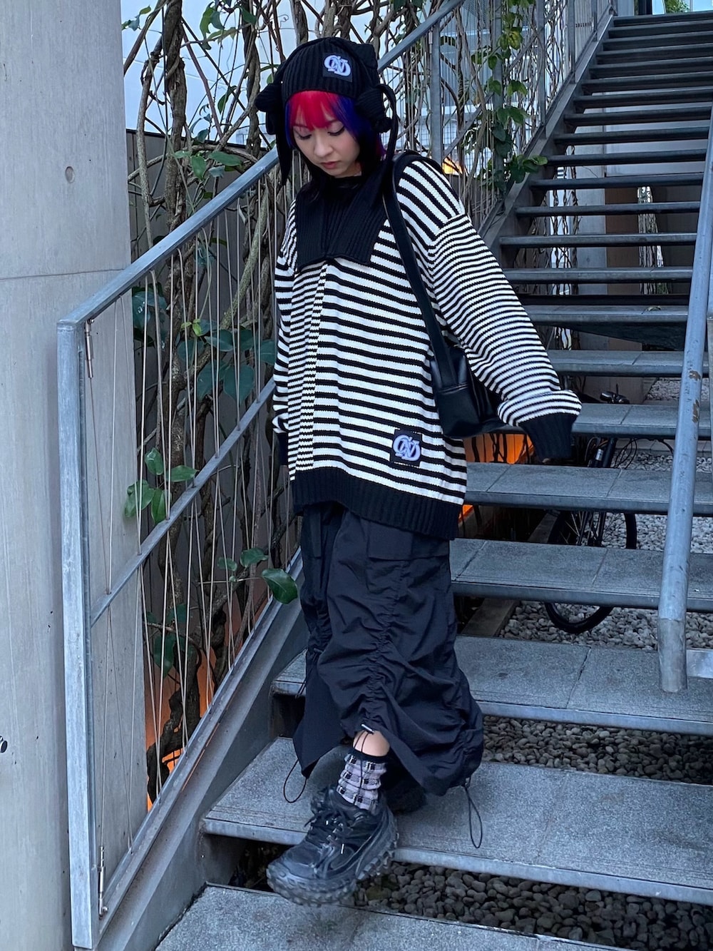 ブラック系のスカート、ブラック系のショルダーバッグ、ブラック系のニット/セーターを着用したレディースの冬コーディネートの2枚目の写真