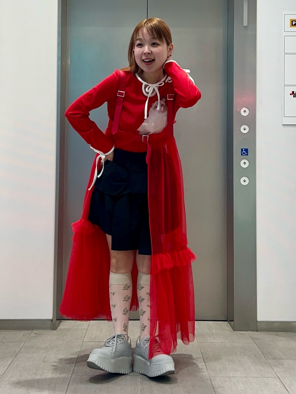 レッド系のスカート、ブラック系のその他パンツ、レッド系のTシャツ/カットソーを着用したレディースの冬コーディネートの2枚目の写真