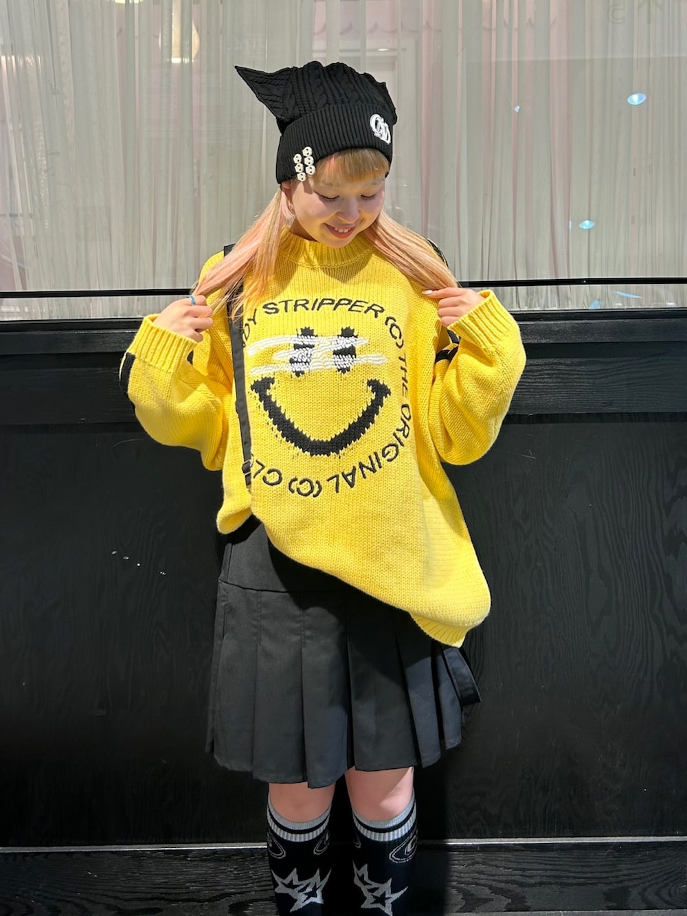 イエロー系のニット/セーター、ブラック系のスカート、ブラック系のニットキャップ/ビーニーを着用したレディースの秋コーディネートの6枚目の写真