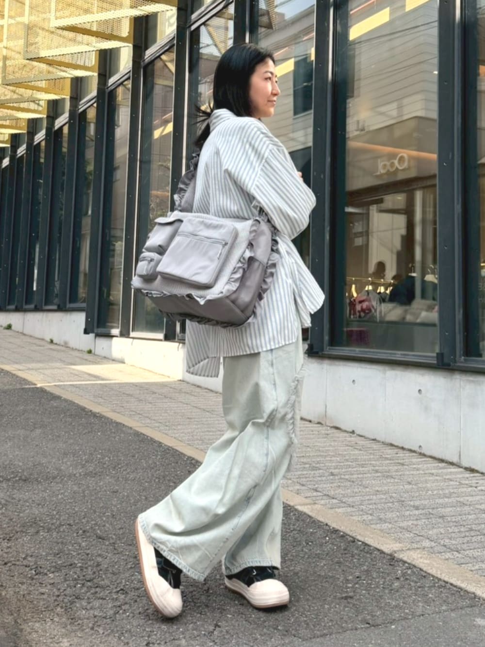 ブルー系のシャツ/ブラウス、グレー系のショルダーバッグ、ブルー系のデニムパンツを着用したレディースの冬コーディネートの2枚目の写真