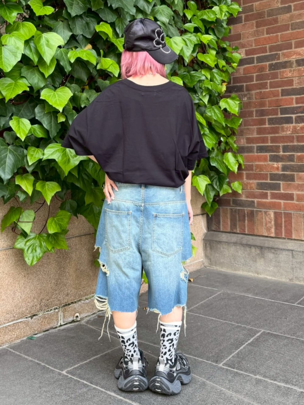 ブルー系のデニムパンツ、ブラック系のTシャツ/カットソー、ブラック系のキャップを着用したレディースの春コーディネートの2枚目の写真