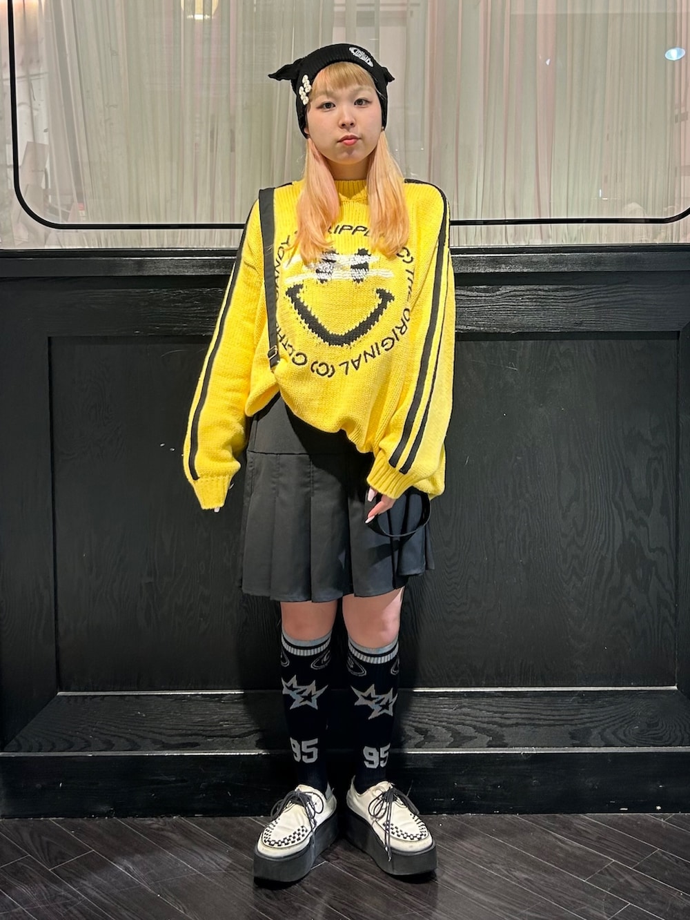 イエロー系のニット/セーター、ブラック系のスカート、ブラック系のニットキャップ/ビーニーを着用したレディースの秋コーディネートの3枚目の写真