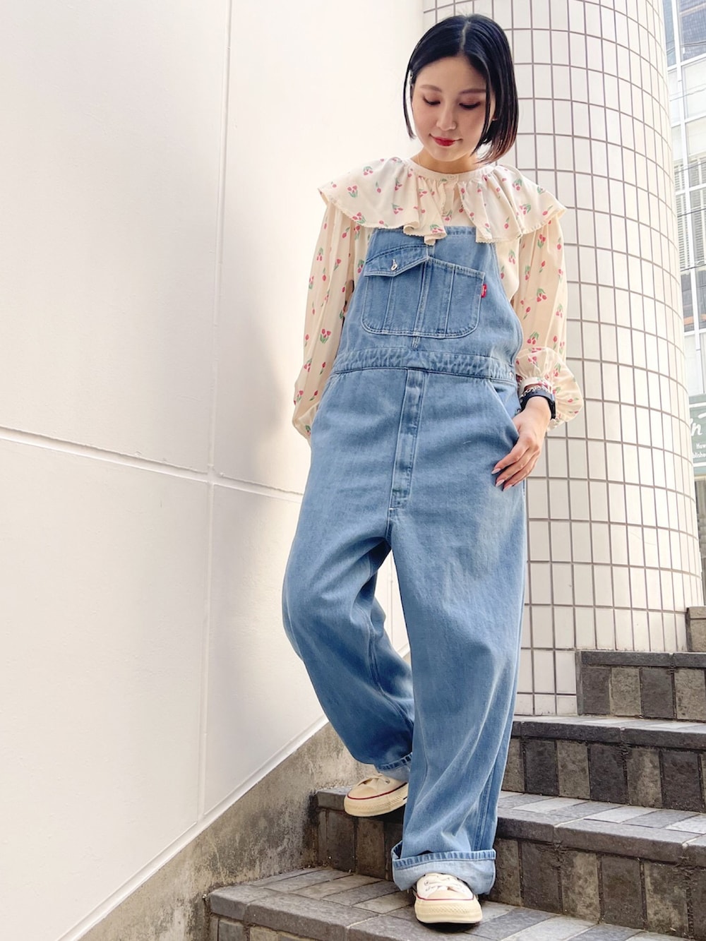 ホワイト系のスニーカー、ブルー系のサロペット/オーバーオール、ホワイト系のシャツ/ブラウスを着用したレディースの春コーディネートの2枚目の写真