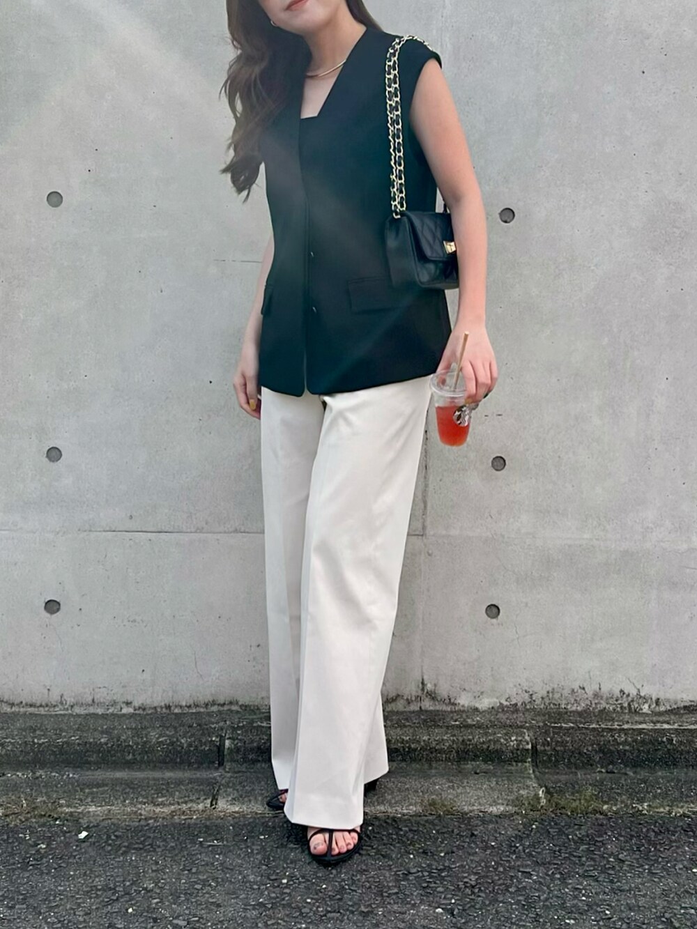 ブラック系のベスト、ホワイト系のその他パンツ、ブラック系のサンダルを着用したレディースの夏コーディネートの2枚目の写真