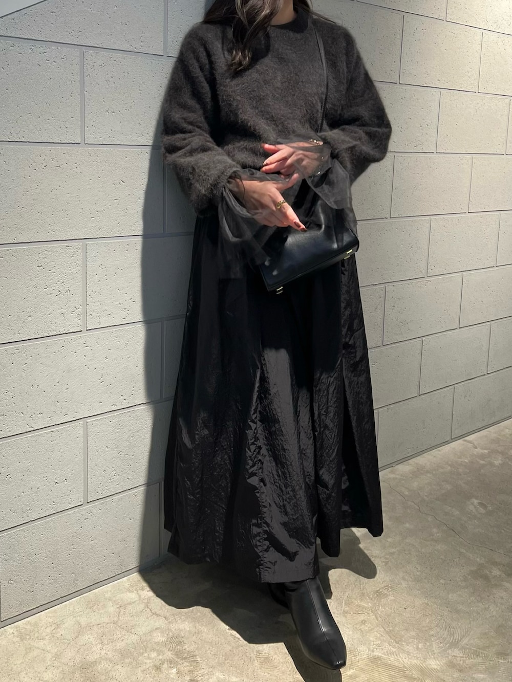 ブラウン系のニット/セーター、ブラック系のスカート、ブラック系のブーツを着用したレディースの秋コーディネートの2枚目の写真