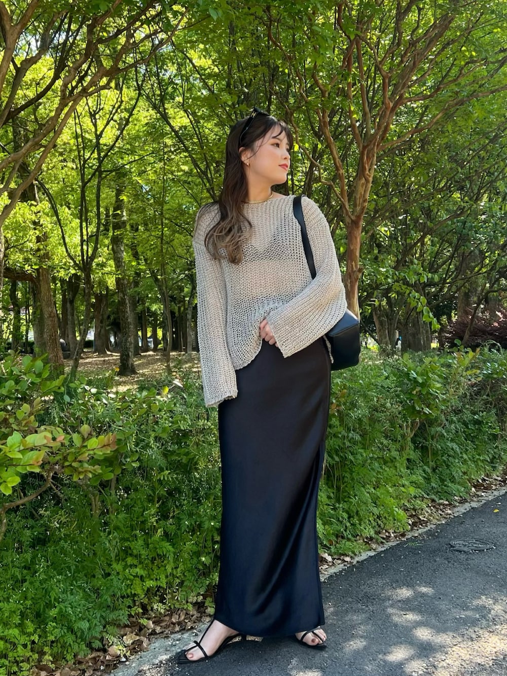 グレー系のニット/セーター、ブラック系のスカート、ブラック系のサンダルを着用したレディースの春コーディネートの2枚目の写真