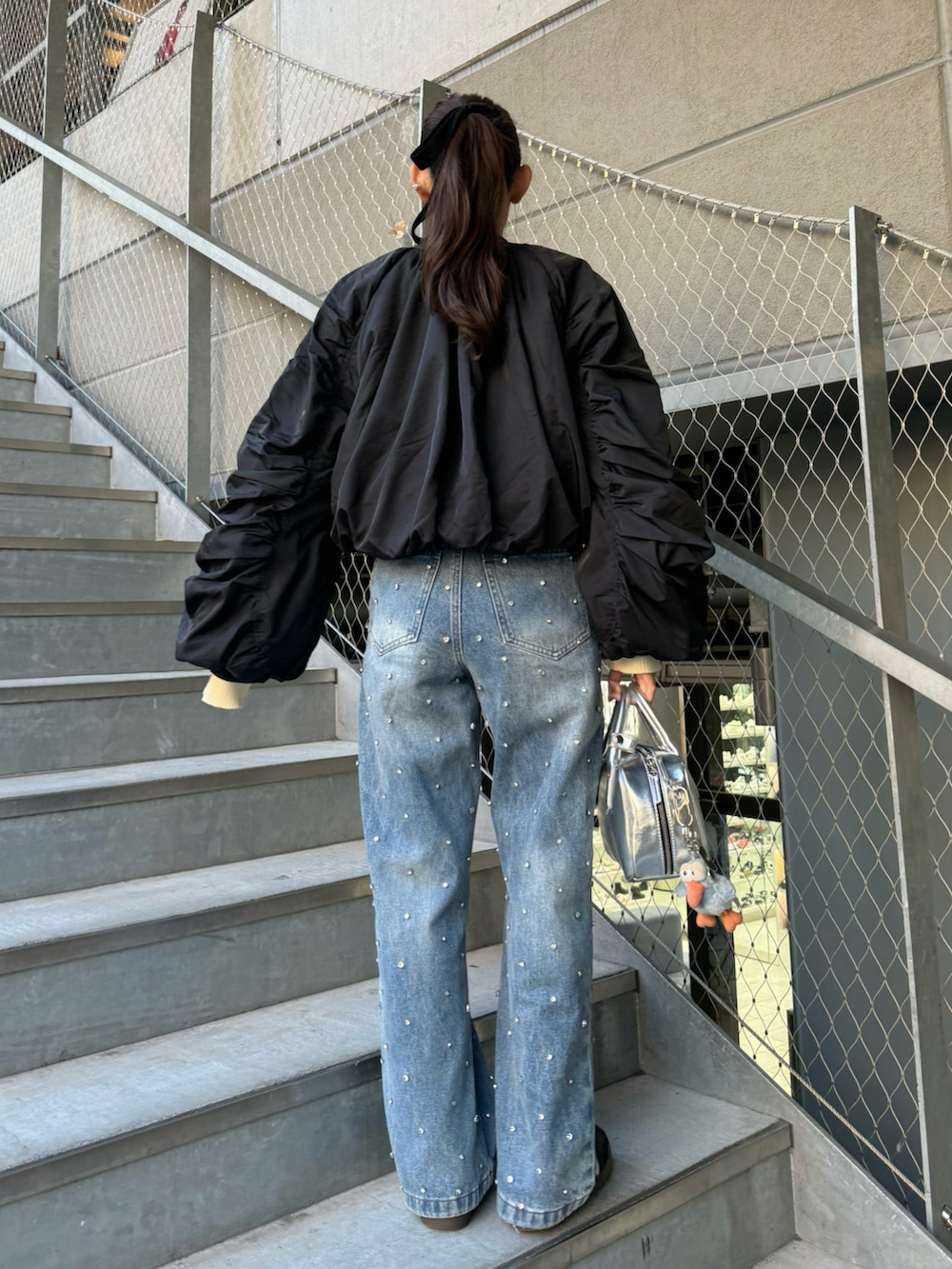 ブラック系のMA-1、ブルー系のデニムパンツ、シルバー系のボストンバッグを着用したレディースの秋コーディネートの4枚目の写真