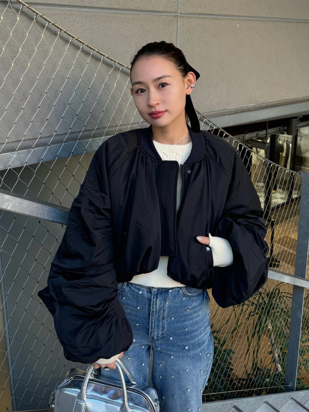 ブラック系のMA-1、ブルー系のデニムパンツ、シルバー系のボストンバッグを着用したレディースの秋コーディネートの2枚目の写真