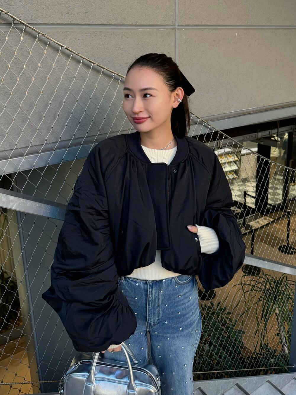 ブラック系のMA-1、ブルー系のデニムパンツ、シルバー系のボストンバッグを着用したレディースの秋コーディネートの3枚目の写真