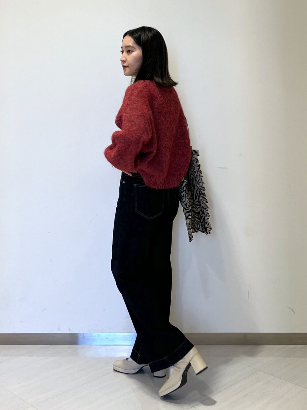 ブルー系のデニムパンツ、レッド系のニット/セーター、ベージュ系のトートバッグを着用したレディースの秋コーディネートの5枚目の写真