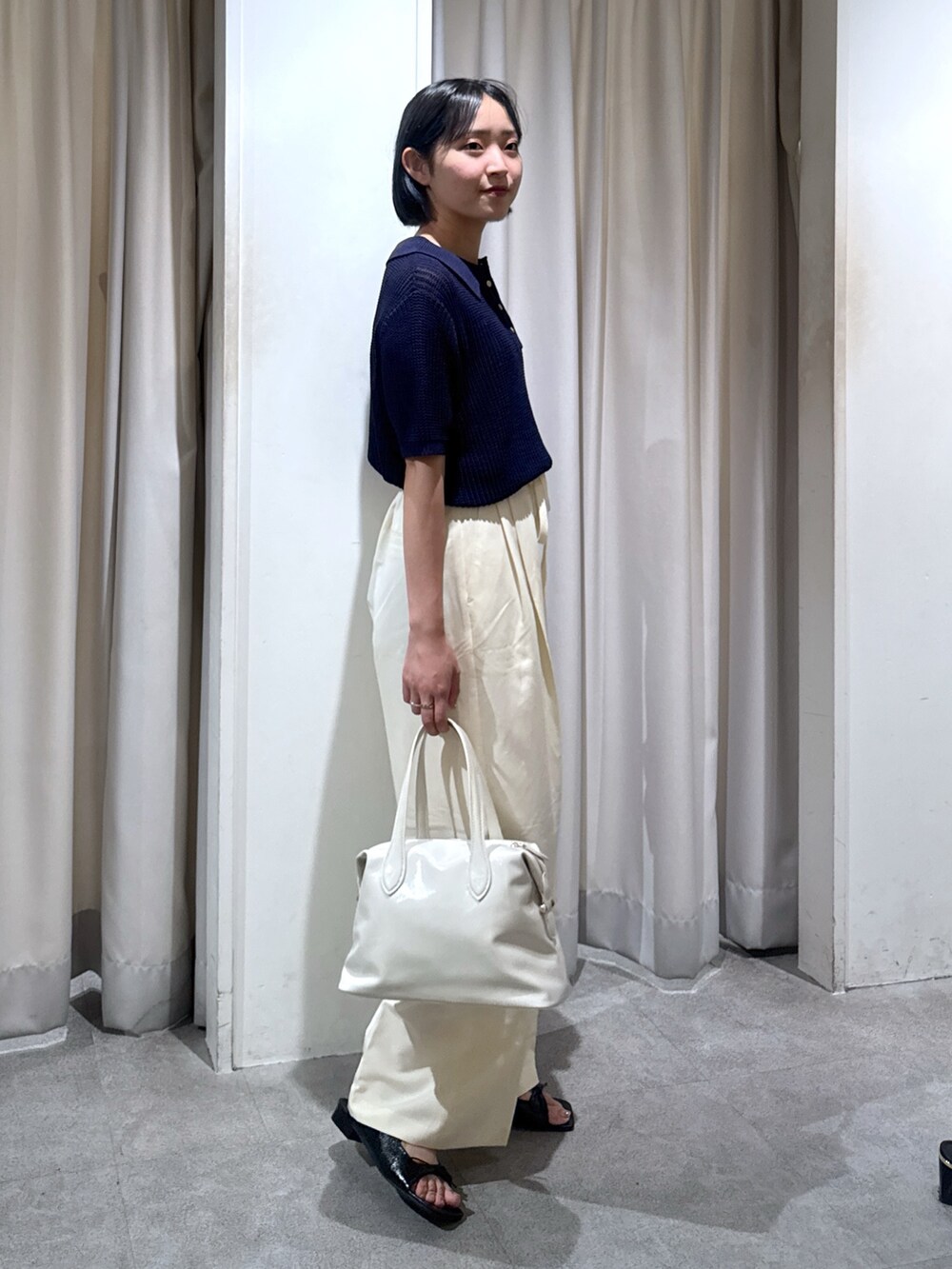 ブルー系のニット/セーター、ホワイト系のスラックス、ホワイト系のショルダーバッグを着用したレディースの夏コーディネートの4枚目の写真