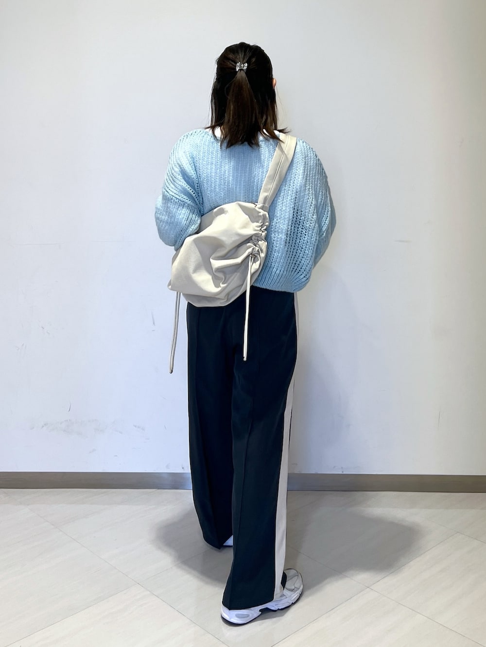 ホワイト系のショルダーバッグ、ブルー系のニット/セーター、ホワイト系のTシャツ/カットソーを着用したレディースの冬コーディネートの5枚目の写真