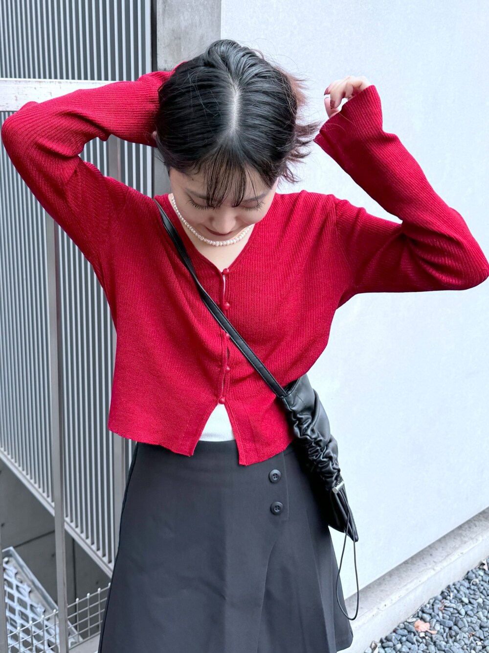 ブラック系のスカート、レッド系のニット/セーター、ブラック系のトートバッグを着用したレディースの秋コーディネートの4枚目の写真