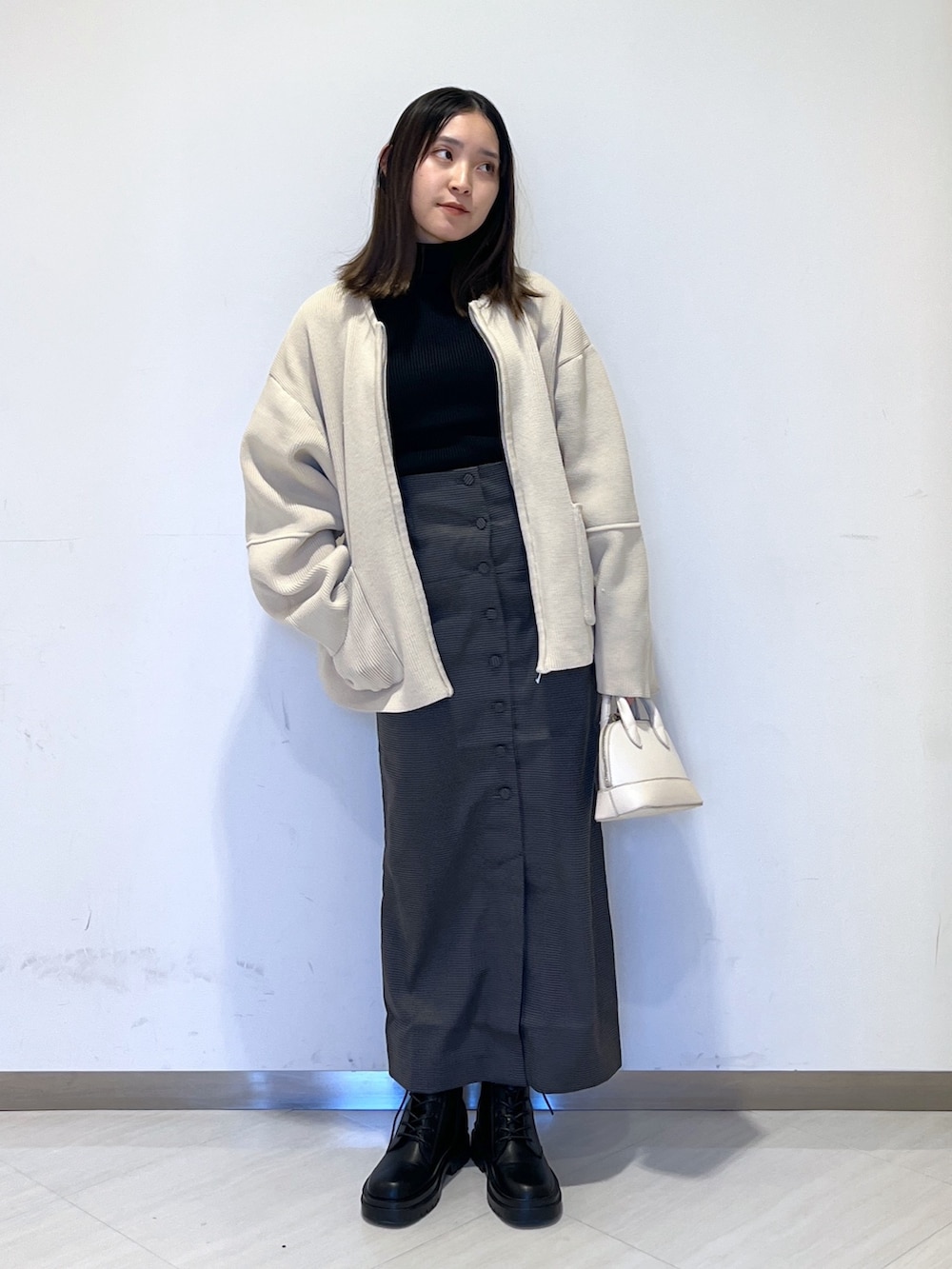 ホワイト系のカーディガン/ボレロ、ブラック系のニット/セーター、ホワイト系のショルダーバッグを着用したレディースの冬コーディネートの2枚目の写真