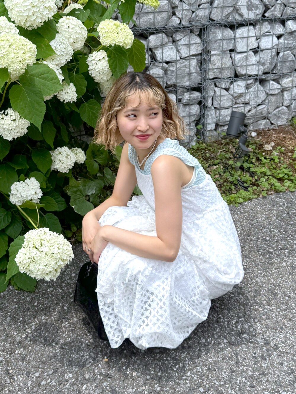 ブルー系のタンクトップ、ホワイト系のワンピース、ブルー系のデニムパンツを着用したレディースの夏コーディネートの4枚目の写真