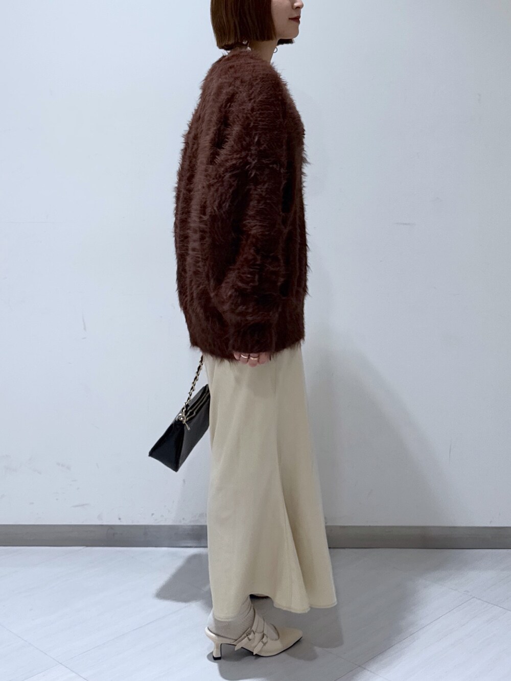 ブラウン系のカーディガン/ボレロ、ホワイト系のタンクトップ、ベージュ系のスカートを着用したレディースの冬コーディネートの4枚目の写真