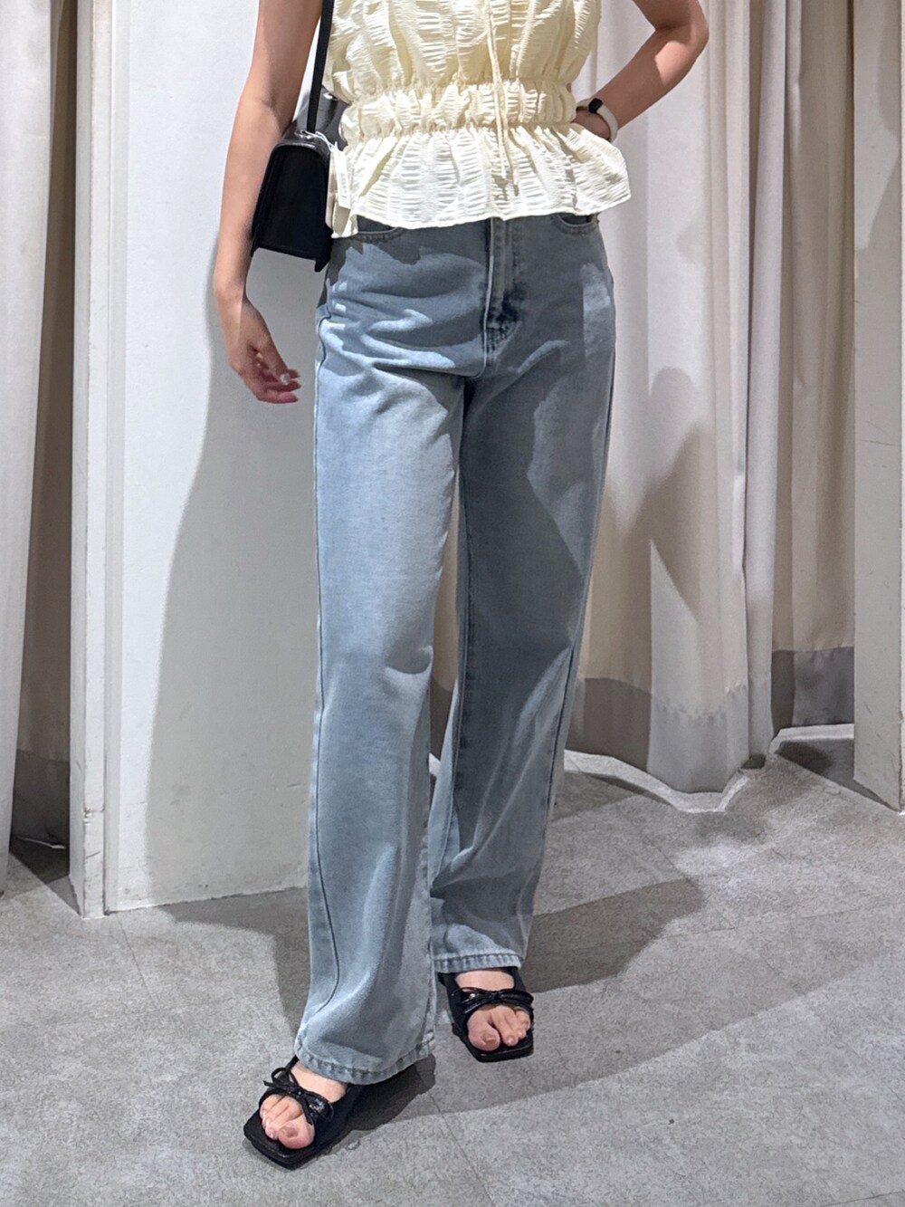 イエロー系のシャツ/ブラウス、ブラック系のショルダーバッグ、ブルー系のデニムパンツを着用したレディースの夏コーディネートの4枚目の写真