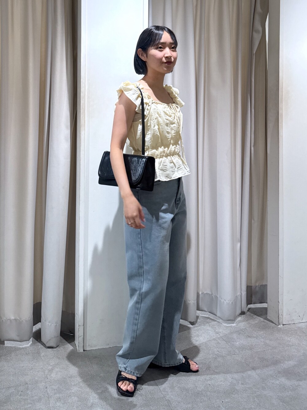 イエロー系のシャツ/ブラウス、ブラック系のショルダーバッグ、ブルー系のデニムパンツを着用したレディースの夏コーディネートの2枚目の写真