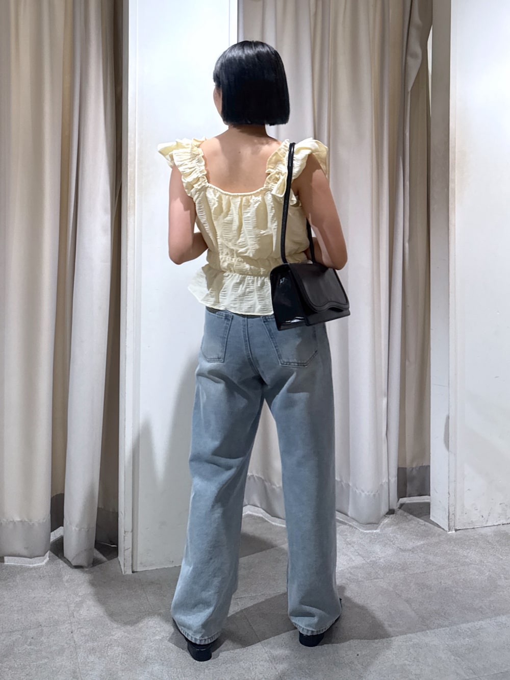 イエロー系のシャツ/ブラウス、ブラック系のショルダーバッグ、ブルー系のデニムパンツを着用したレディースの夏コーディネートの5枚目の写真