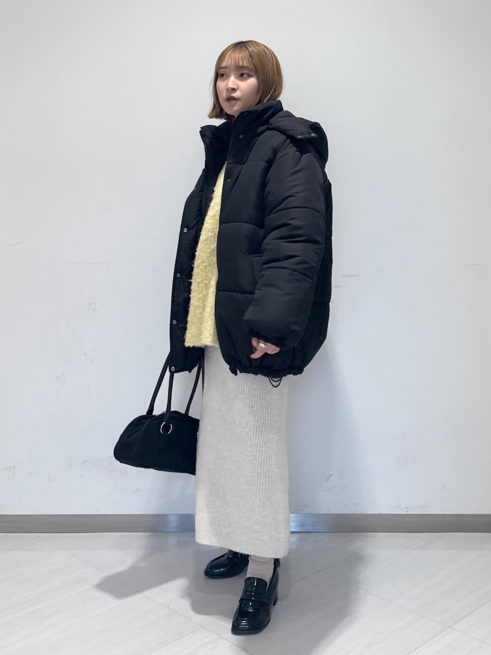 ブラック系のダウンジャケット/コート、イエロー系のニット/セーター、ブラック系のトートバッグを着用したレディースの冬コーディネートの4枚目の写真