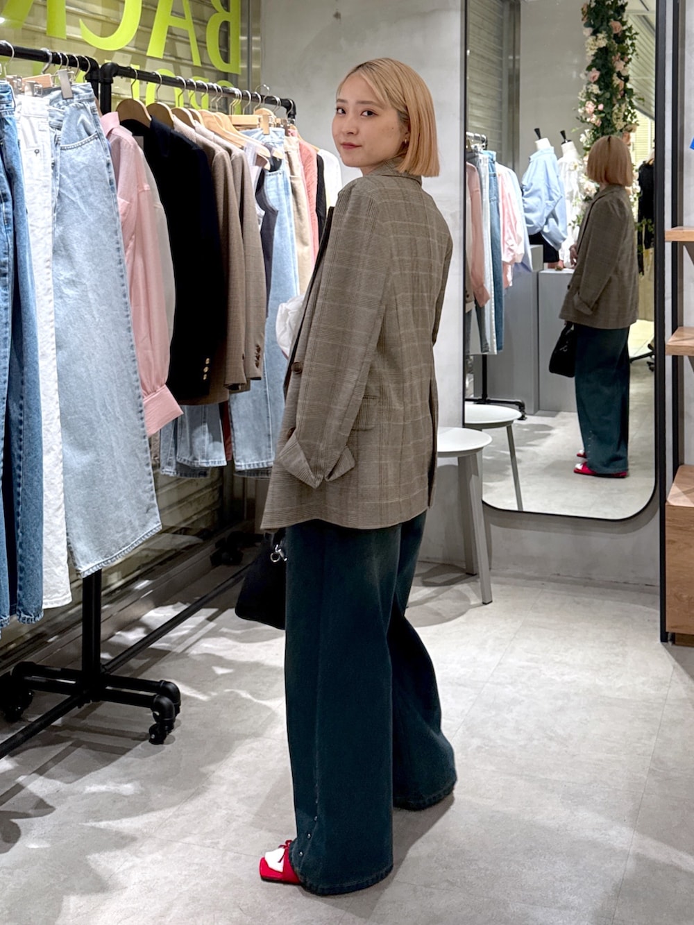 グレー系のテーラードジャケット、ホワイト系のシャツ/ブラウス、ブルー系のデニムパンツを着用したレディースの夏コーディネートの2枚目の写真