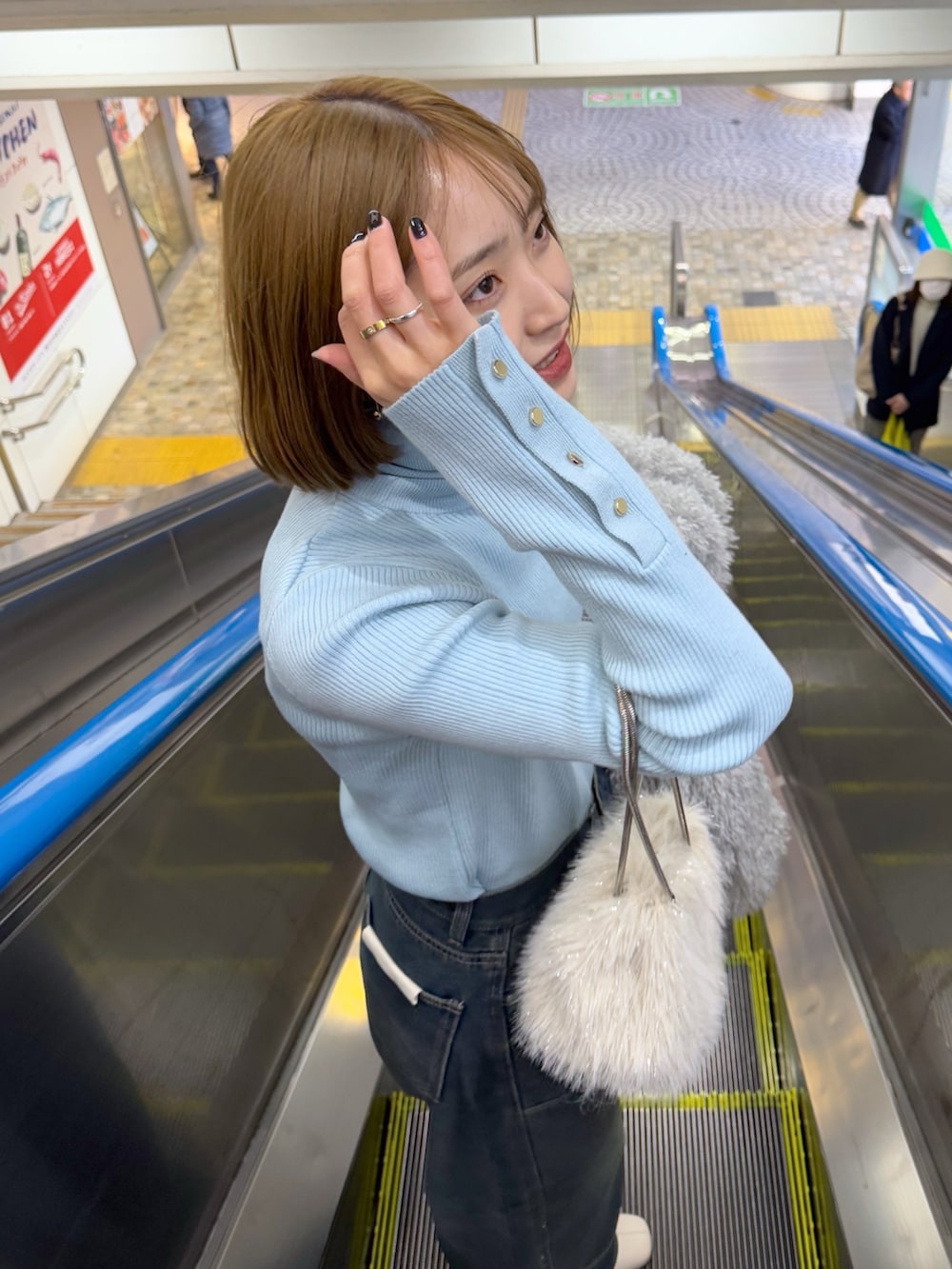 グレー系のブルゾン、ブルー系のニット/セーター、ベージュ系のショルダーバッグを着用したレディースの冬コーディネートの3枚目の写真