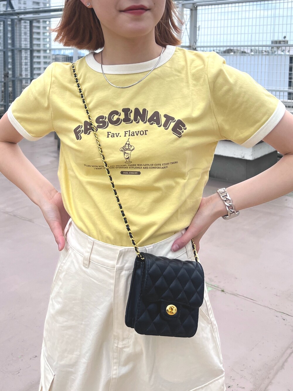 ホワイト系のスカート、イエロー系のTシャツ/カットソー、ブラック系のショルダーバッグを着用したレディースの夏コーディネートの5枚目の写真