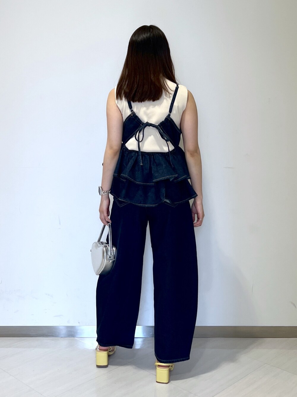 ホワイト系のニット/セーター、ブルー系のベスト、ブルー系のデニムパンツを着用したレディースの春コーディネートの5枚目の写真