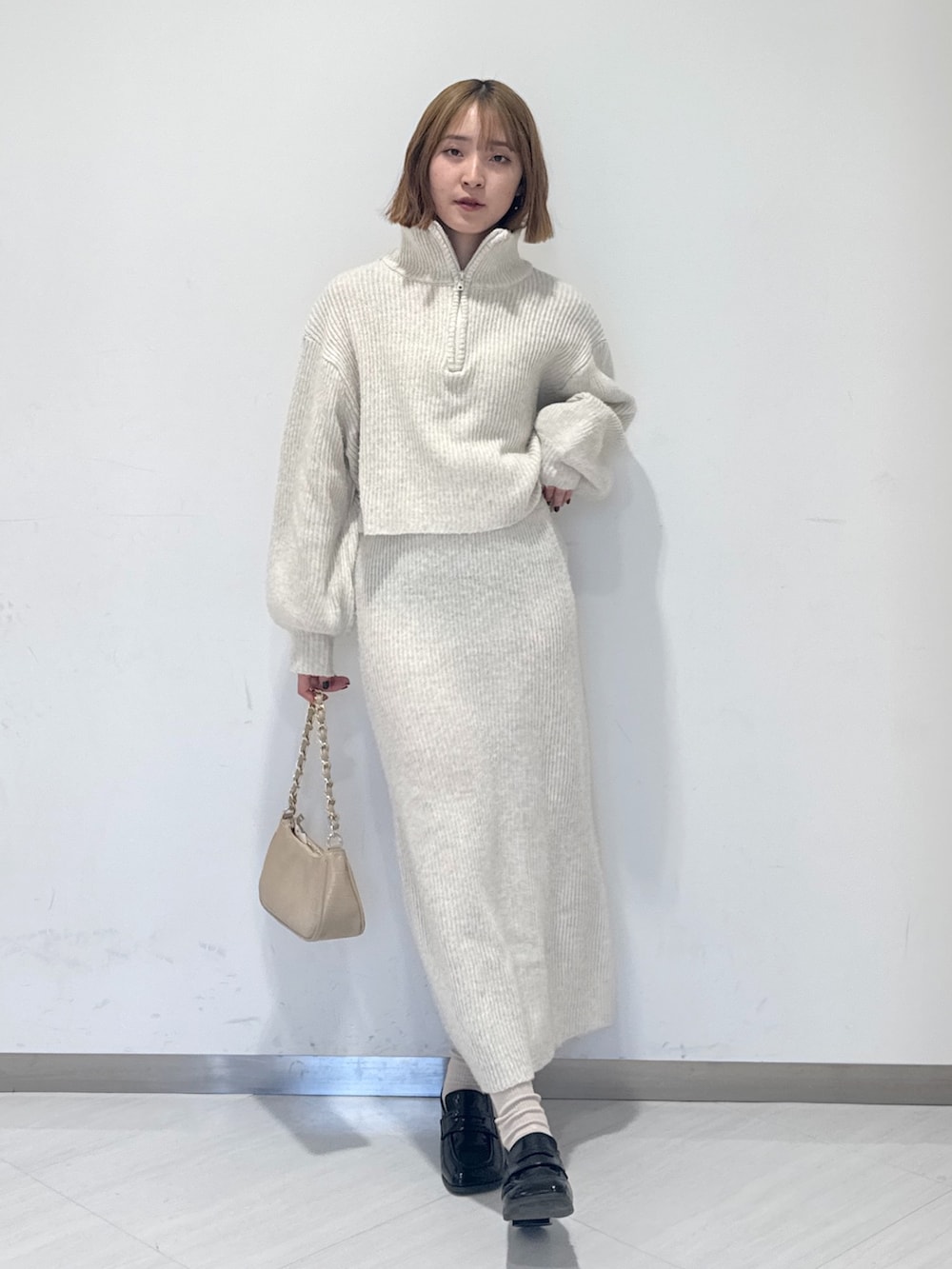 ホワイト系のワンピース、ベージュ系のトートバッグ、ブラック系のローファーを着用したレディースの冬コーディネートの5枚目の写真