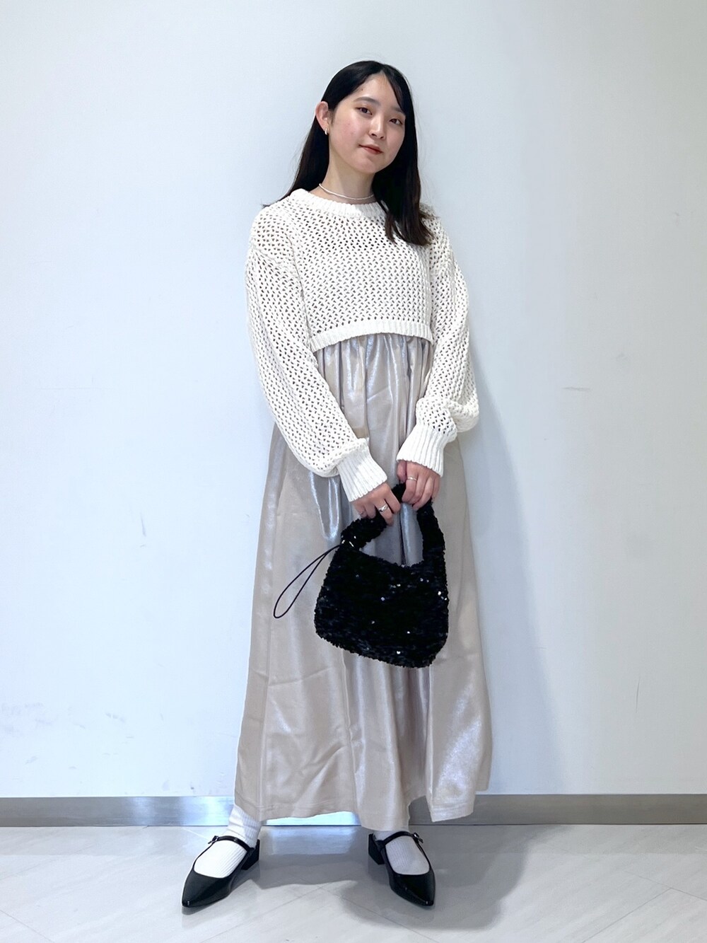 ベージュ系のニット/セーター、ブラック系のハンドバッグ、ベージュ系のワンピースを着用したレディースの春コーディネートの3枚目の写真