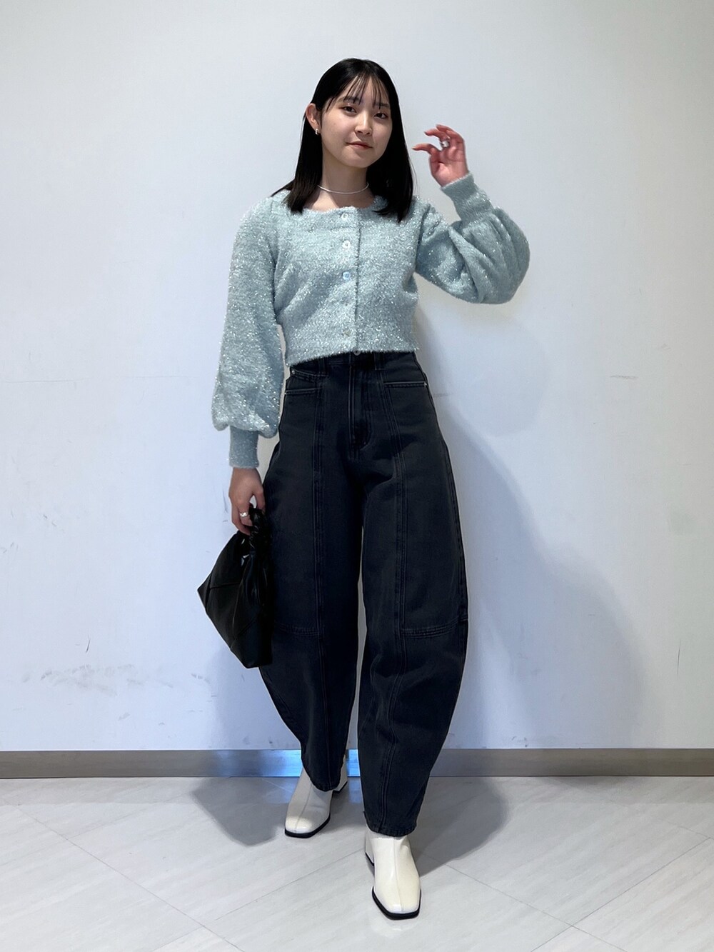 グリーン系のニット/セーター、ブラック系のデニムパンツ、ブラック系のショルダーバッグを着用したレディースの冬コーディネートの2枚目の写真