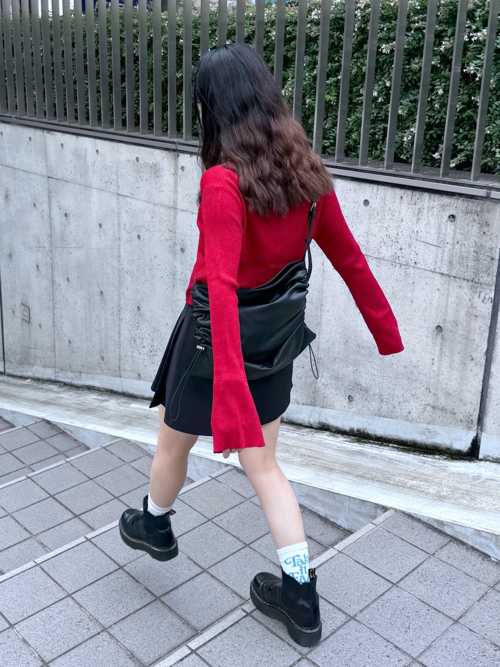 ブラック系のスカート、レッド系のニット/セーター、ブラック系のトートバッグを着用したレディースの秋コーディネートの5枚目の写真