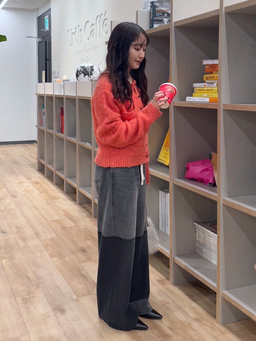 ピンク系のカーディガン/ボレロ、ブラック系のデニムパンツ、ベージュ系のショルダーバッグを着用したレディースの冬コーディネートの2枚目の写真