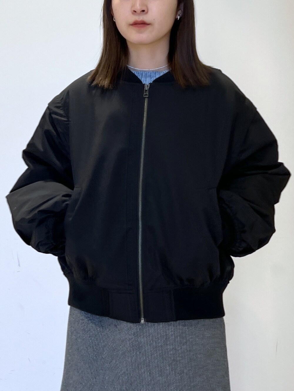 ブラック系のMA-1、ブルー系のニット/セーター、ブラック系のスカートを着用したレディースの冬コーディネートの2枚目の写真