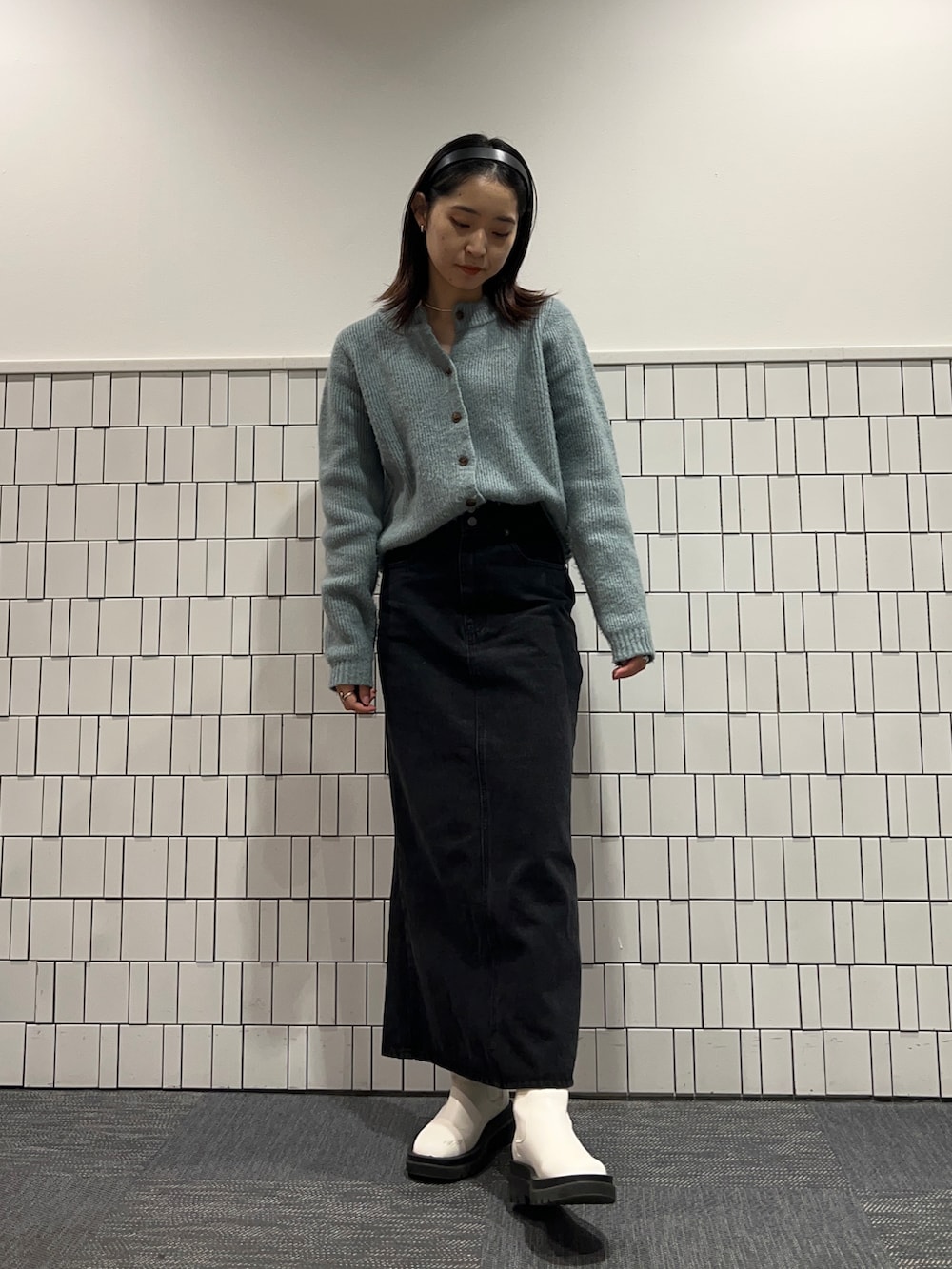 グリーン系のニット/セーター、ブラック系のデニムスカート、ホワイト系のブーツを着用したレディースの冬コーディネートの3枚目の写真