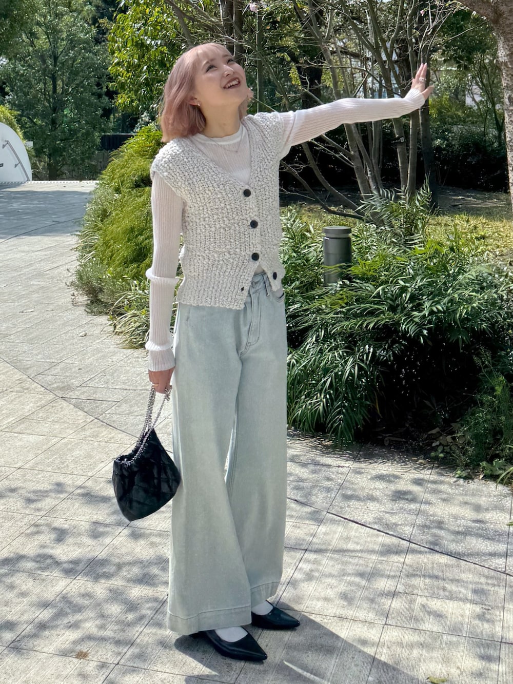 ホワイト系のベスト、ホワイト系のニット/セーター、ブルー系のデニムパンツを着用したレディースの春コーディネートの2枚目の写真