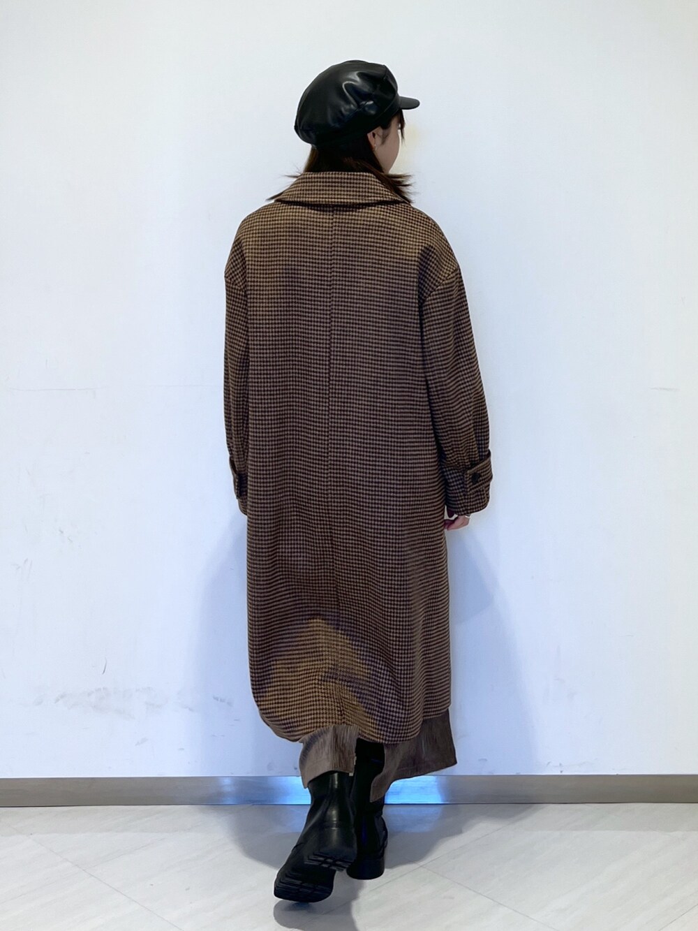 ブラウン系のチェスターコート、ブラック系のニット/セーター、ブラウン系のスカートを着用したレディースの冬コーディネートの5枚目の写真