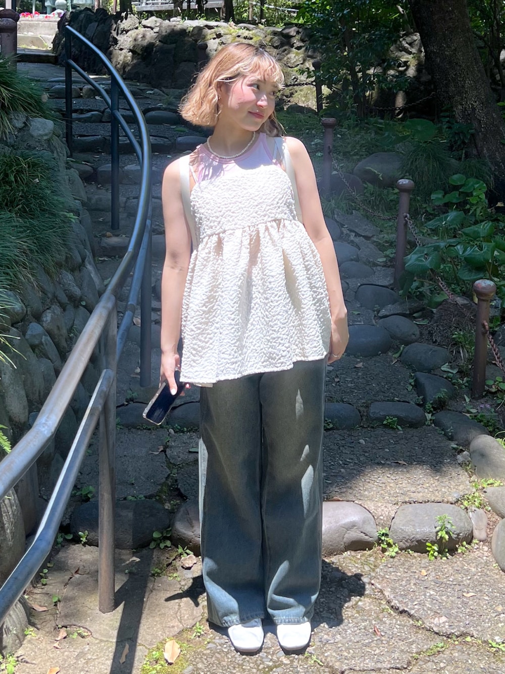 ピンク系のタンクトップ、ホワイト系のキャミソール、ブルー系のデニムパンツを着用したレディースの夏コーディネートの4枚目の写真