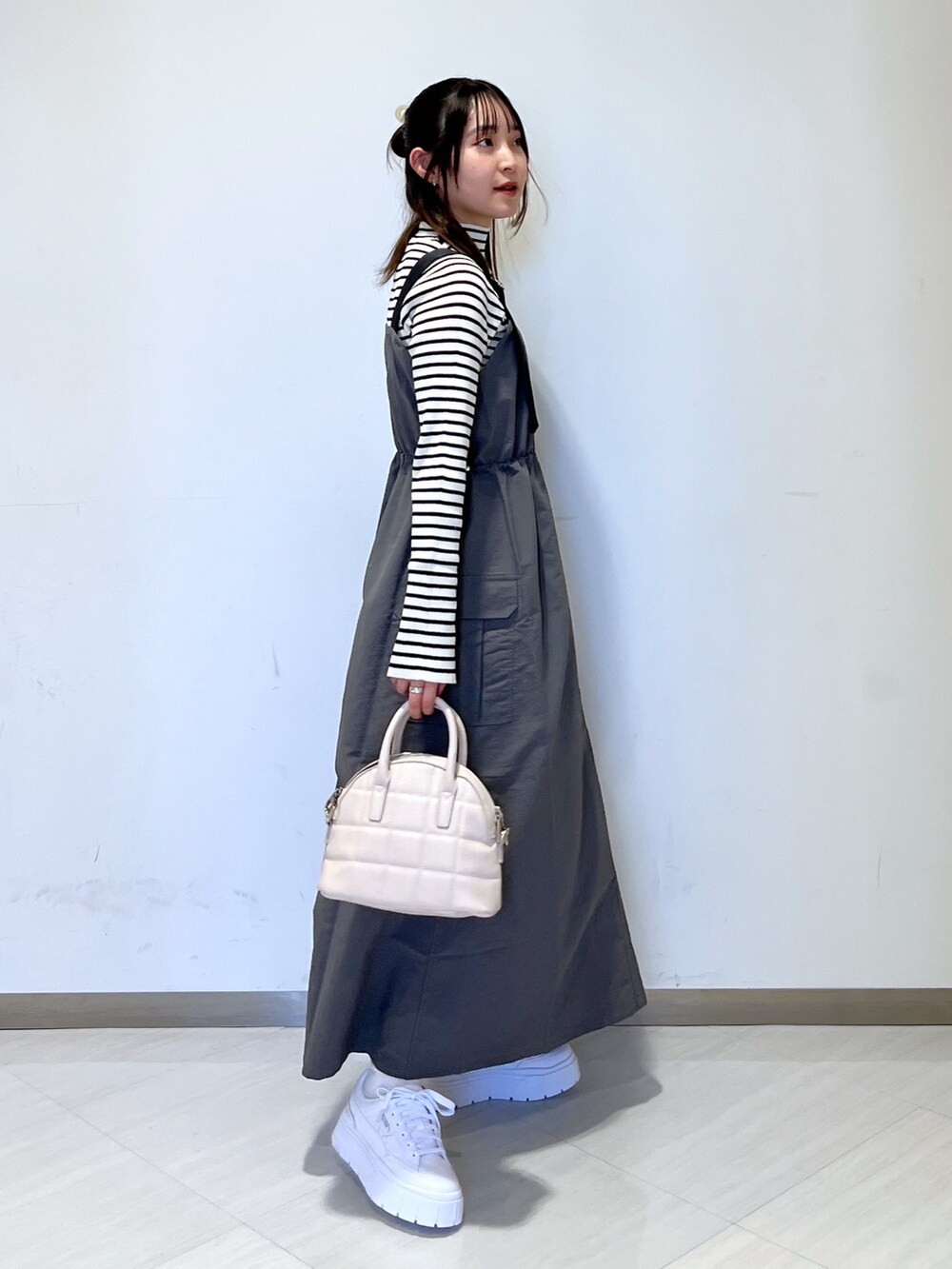 グレー系のワンピース、ホワイト系のハンドバッグ、ホワイト系のニット/セーターを着用したレディースの冬コーディネートの3枚目の写真