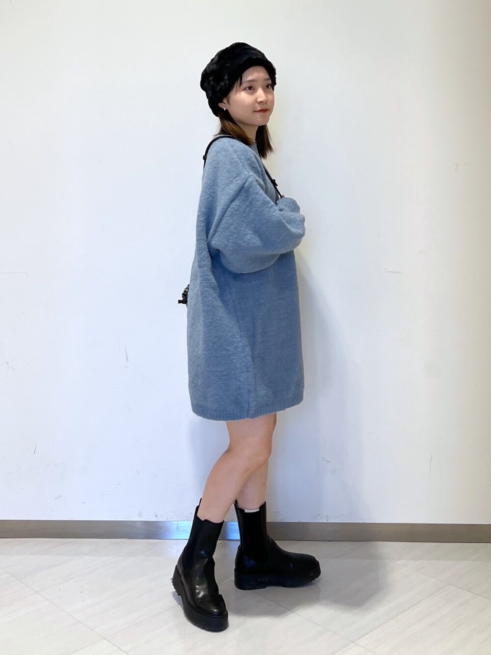 ブルー系のワンピース、ブラック系のハンドバッグ、ブラック系のハットを着用したレディースの冬コーディネートの3枚目の写真