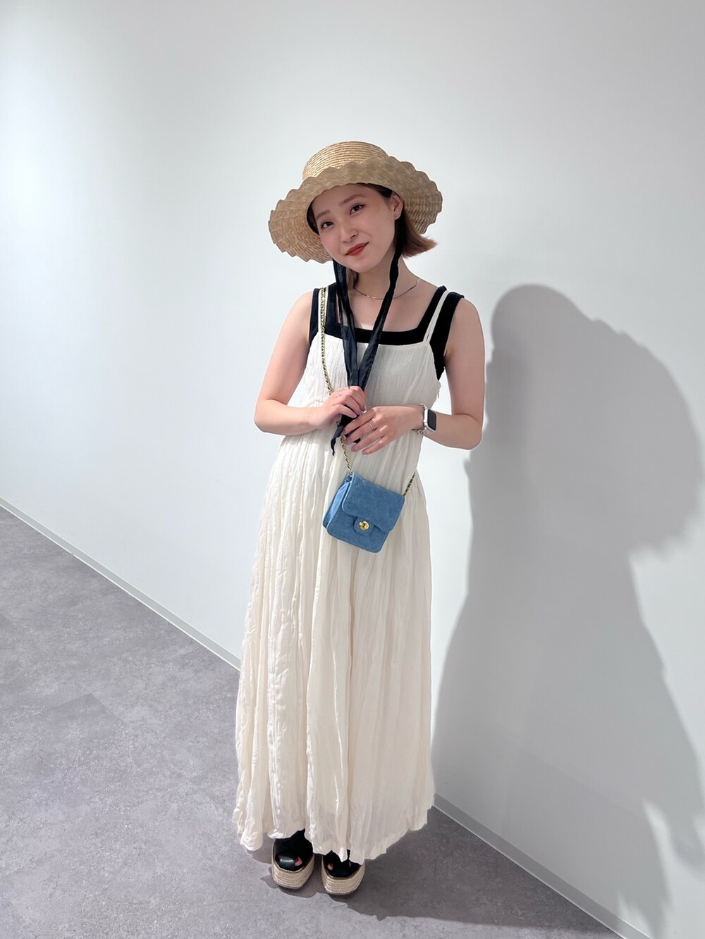 ブラック系のニット/セーター、ホワイト系のワンピース、ブルー系のショルダーバッグを着用したレディースの夏コーディネートの5枚目の写真