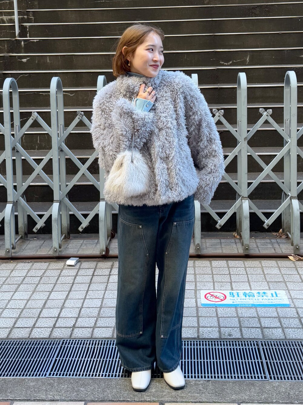 グレー系のブルゾン、ブルー系のニット/セーター、ベージュ系のショルダーバッグを着用したレディースの冬コーディネートの2枚目の写真